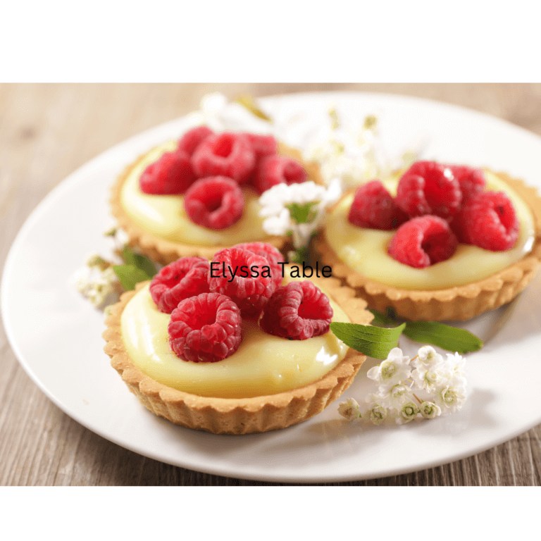 Lemon Raspberry Tart with a buttery crust, lemon filling, and fresh raspberry topping, garnished with mint leaves.