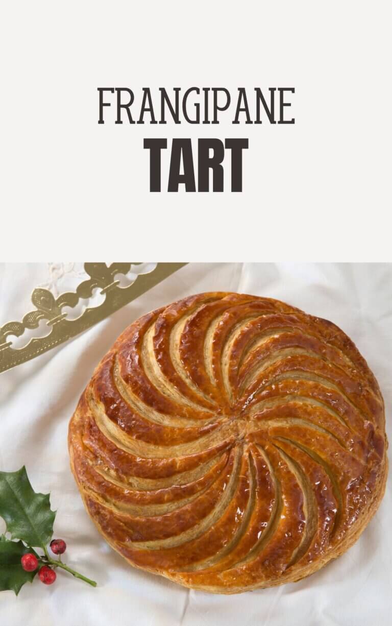 A beautifully baked Frangipane Tart topped with golden pear slices and a dusting of powdered sugar, served on a rustic wooden table.